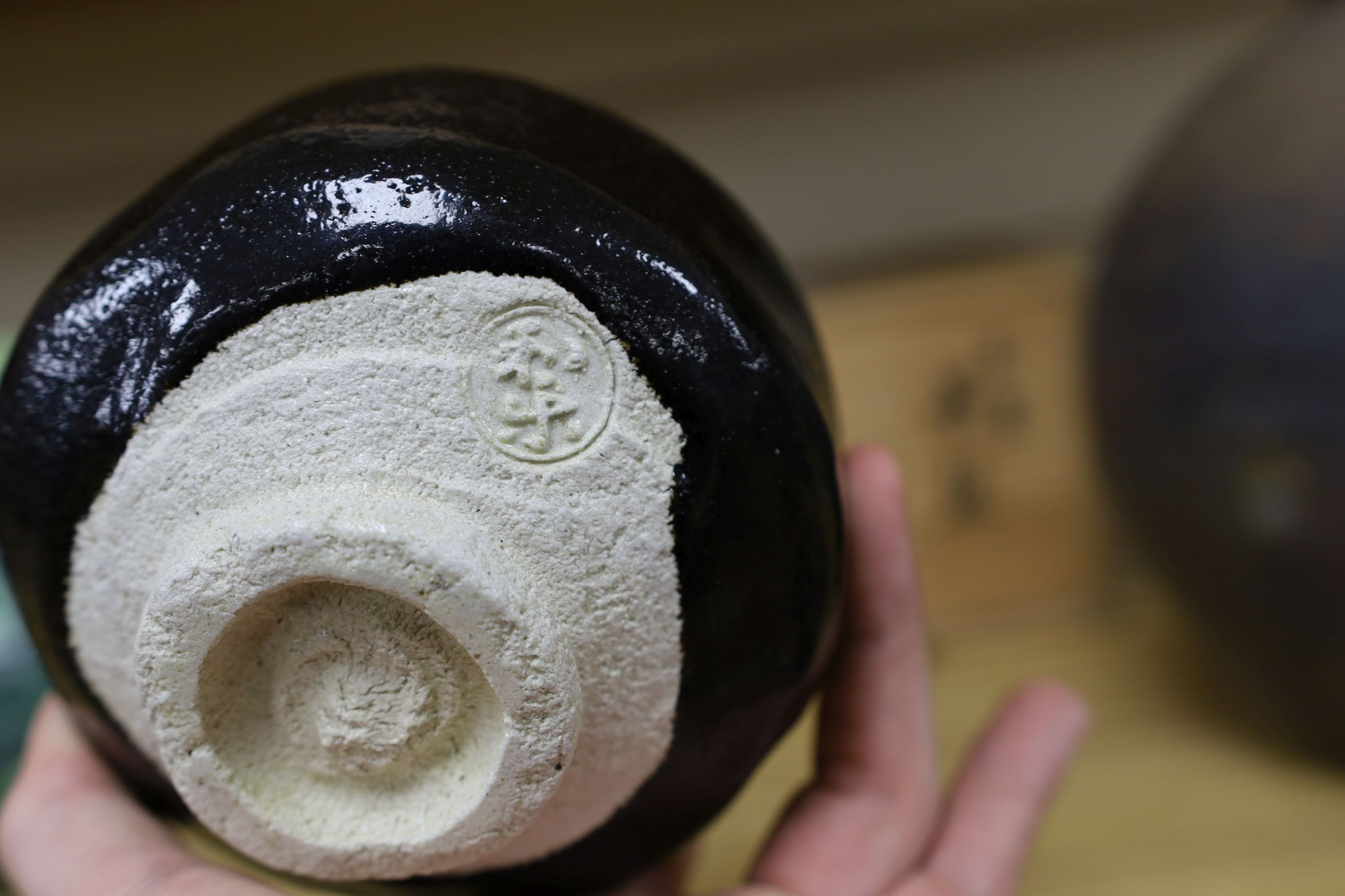 Japanese studio pottery: a boxed black glaze stoneware unomi tea bowl, with impressed mark, together with a ovoid vase, marked, 21cm tall
